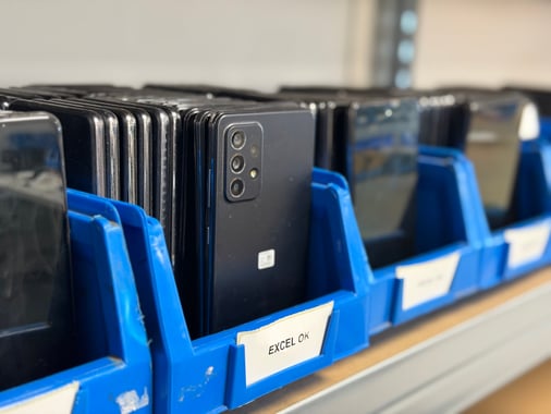 Smartphones reconditionnés triés par grade dans les bacs de tri de l atelier Phoner